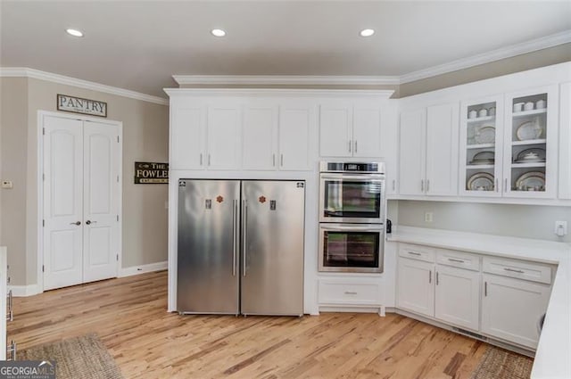 kitchen featuring white cabinets, light wood-type flooring, stainless steel appliances, and crown molding