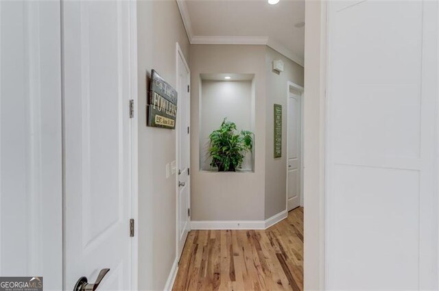 hall with crown molding and light hardwood / wood-style flooring