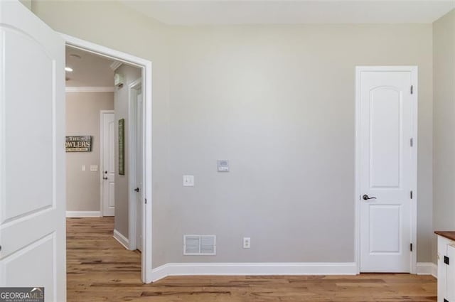 spare room featuring light hardwood / wood-style floors and crown molding