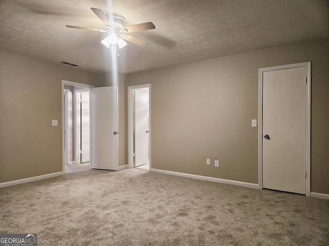 unfurnished room with ceiling fan, carpet flooring, and a textured ceiling