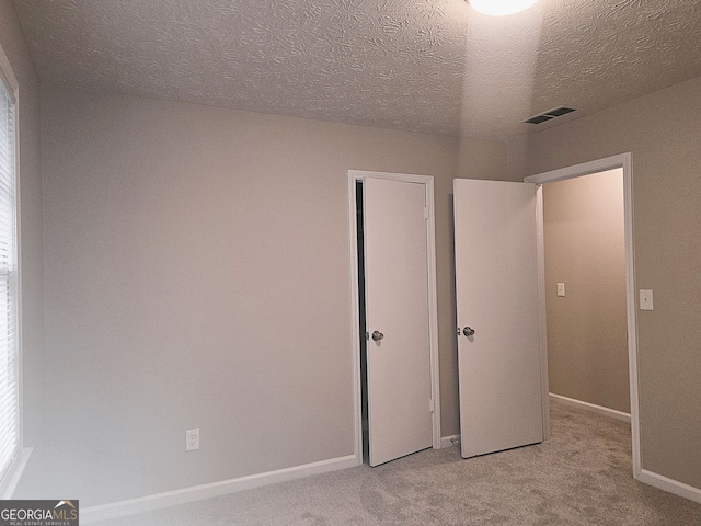 unfurnished bedroom featuring light carpet and a textured ceiling