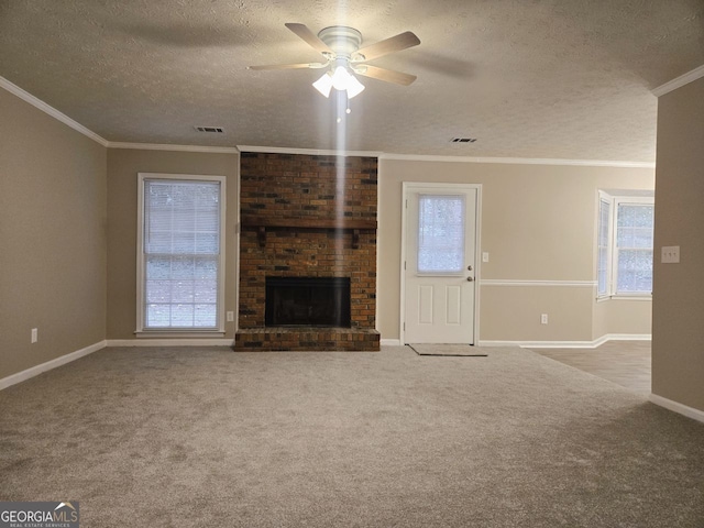 unfurnished living room with a wealth of natural light, a textured ceiling, a fireplace, light colored carpet, and crown molding