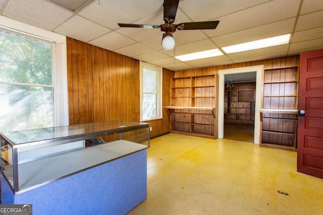 unfurnished office with a paneled ceiling, a wealth of natural light, and wood walls