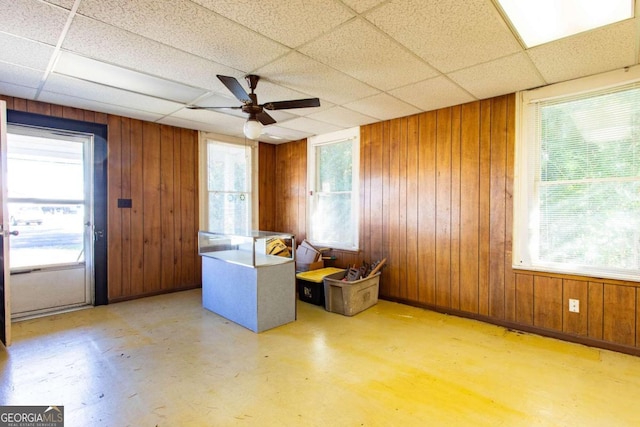 interior space with a paneled ceiling, plenty of natural light, and wood walls