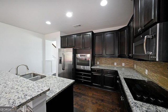 kitchen featuring backsplash, sink, dark hardwood / wood-style floors, light stone countertops, and stainless steel appliances