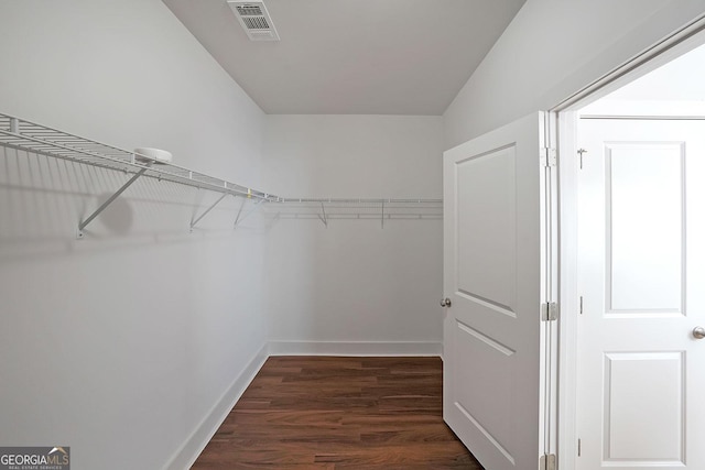 walk in closet with dark hardwood / wood-style flooring