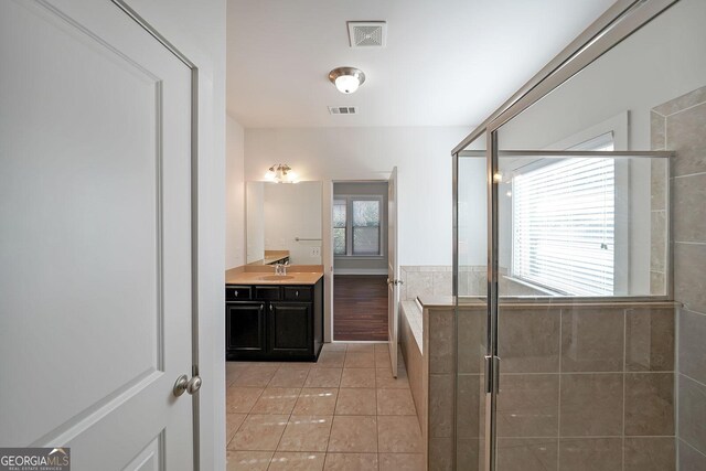 bathroom with vanity, tile patterned floors, a shower with door, and a healthy amount of sunlight