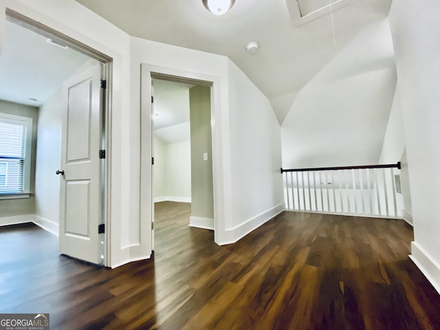 additional living space featuring dark wood-type flooring and vaulted ceiling