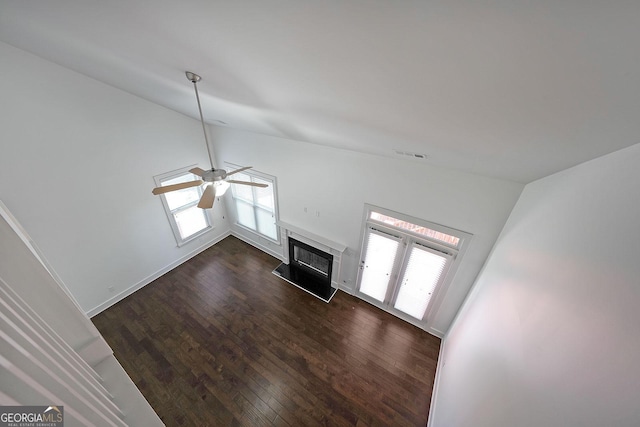 unfurnished living room featuring dark hardwood / wood-style floors, ceiling fan, lofted ceiling, and a fireplace