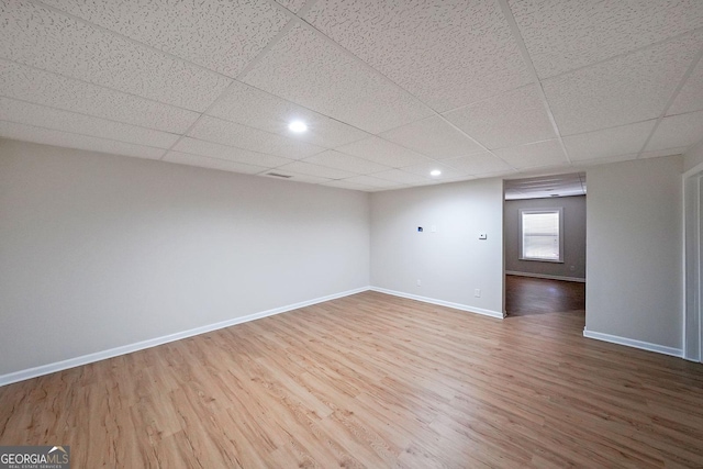 spare room with a drop ceiling and hardwood / wood-style flooring