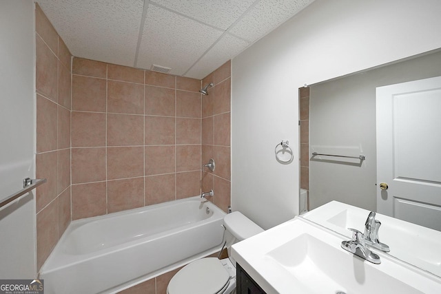 full bathroom featuring vanity, a paneled ceiling, tiled shower / bath combo, and toilet