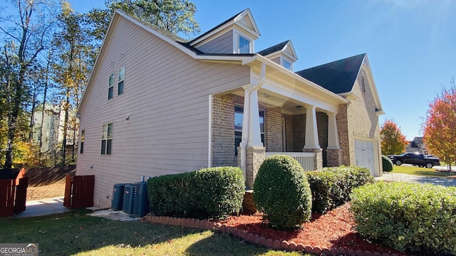 view of home's exterior with a garage, covered porch, and cooling unit