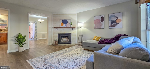 living room featuring a large fireplace, hardwood / wood-style floors, and a notable chandelier