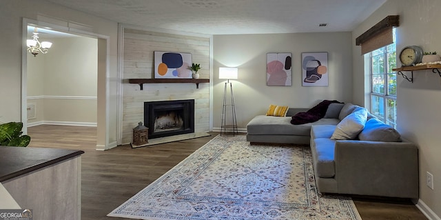 living room with a textured ceiling, dark hardwood / wood-style flooring, a fireplace, and a chandelier