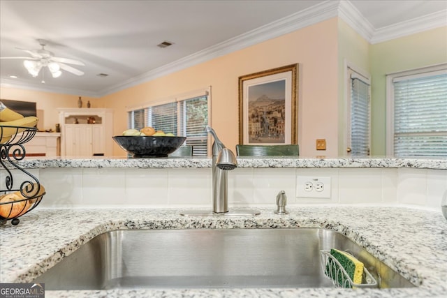 interior details featuring light stone countertops, ceiling fan, ornamental molding, and sink