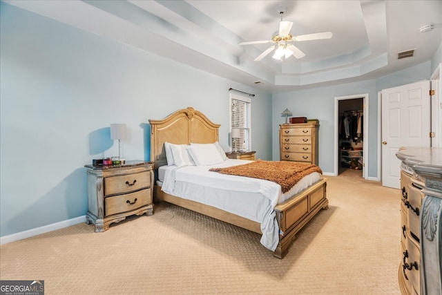 carpeted bedroom featuring a closet, a spacious closet, ceiling fan, and a tray ceiling