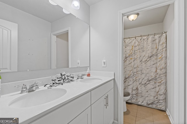 full bathroom featuring toilet, double vanity, a sink, and tile patterned floors