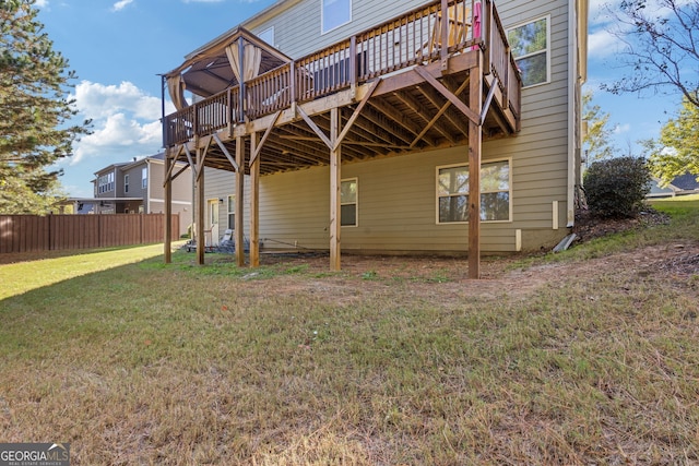 rear view of property with a lawn, a deck, and fence