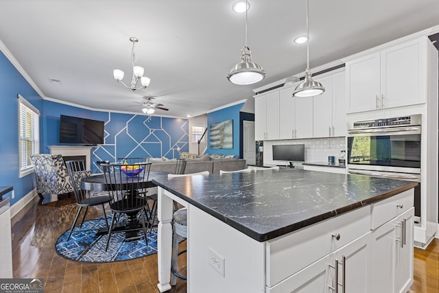 kitchen with an accent wall, open floor plan, a fireplace, and ornamental molding