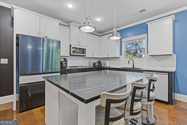 kitchen with visible vents, stainless steel appliances, a sink, and ornamental molding