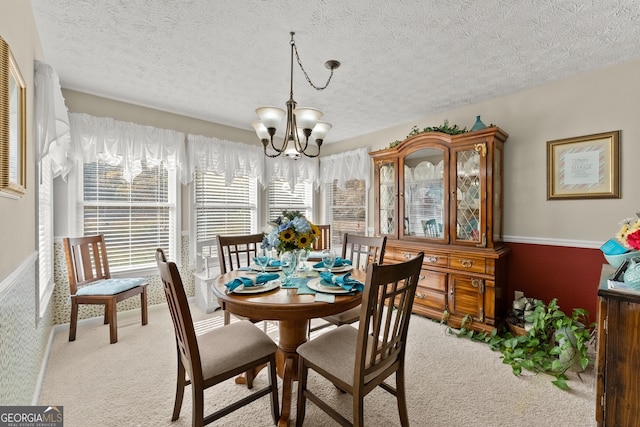 dining space with a textured ceiling, light carpet, and an inviting chandelier