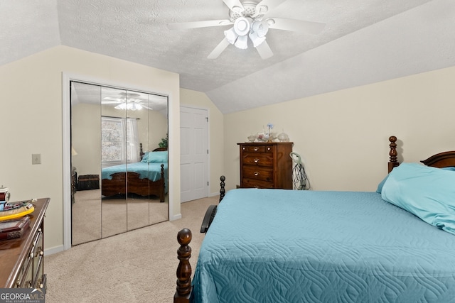 bedroom with ceiling fan, a closet, light carpet, and vaulted ceiling