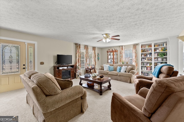 living room with light carpet, ceiling fan, and a textured ceiling