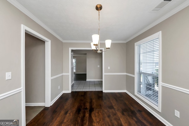 unfurnished dining area with a textured ceiling, a notable chandelier, dark hardwood / wood-style flooring, and crown molding