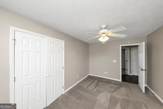 unfurnished bedroom with ceiling fan, a closet, carpet floors, and a textured ceiling