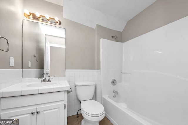 full bathroom featuring washtub / shower combination, tile patterned floors, toilet, vanity, and tile walls