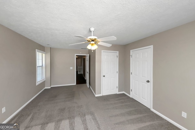 spare room with dark colored carpet, ceiling fan, and a textured ceiling