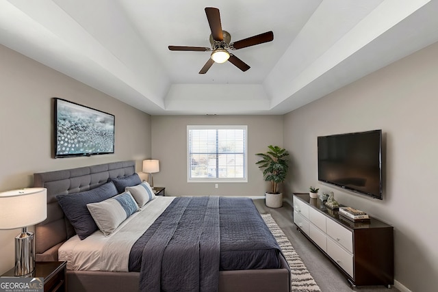 carpeted bedroom featuring a raised ceiling and ceiling fan