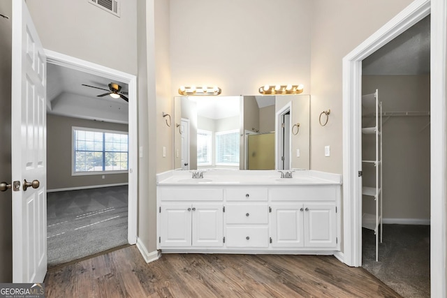 bathroom featuring hardwood / wood-style flooring, ceiling fan, walk in shower, and vanity