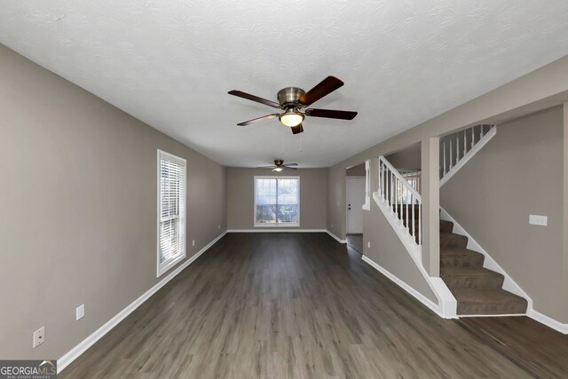 unfurnished living room featuring a textured ceiling, ceiling fan, and dark wood-type flooring