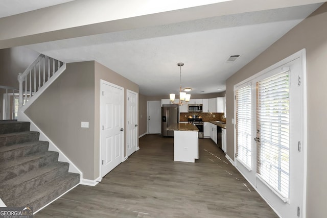 kitchen featuring white cabinets, dark hardwood / wood-style flooring, stainless steel appliances, and hanging light fixtures