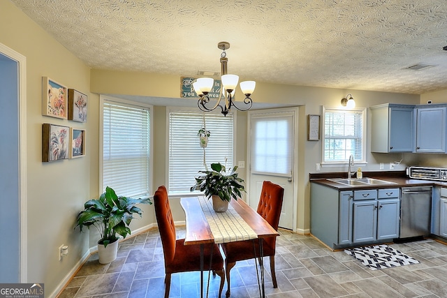 dining room with a textured ceiling, sink, and an inviting chandelier