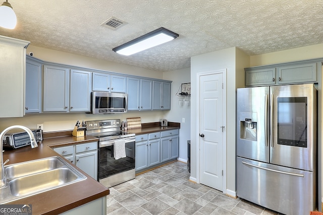 kitchen featuring appliances with stainless steel finishes, a textured ceiling, and sink