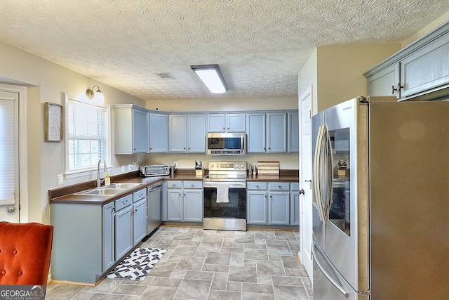 kitchen featuring a textured ceiling, sink, and stainless steel appliances