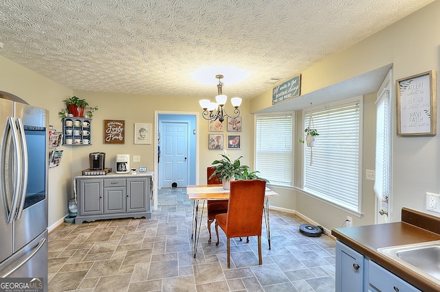 dining room with sink, a textured ceiling, and an inviting chandelier