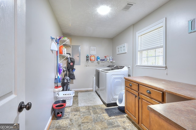 laundry room featuring separate washer and dryer, electric panel, cabinets, and a textured ceiling