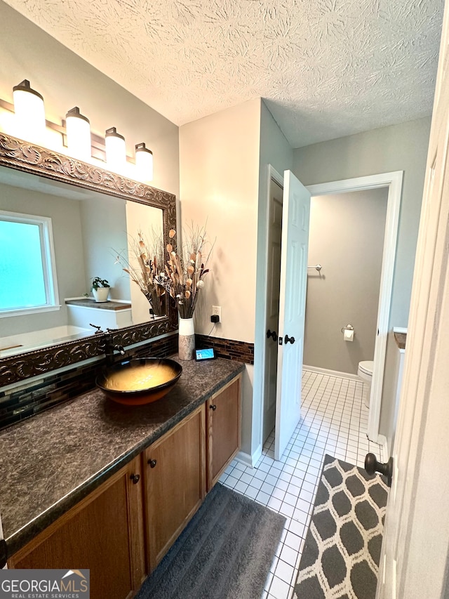 bathroom featuring toilet, vanity, a textured ceiling, and tile patterned floors