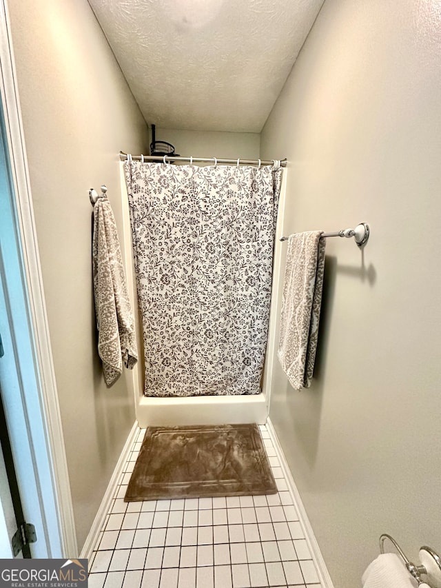 bathroom featuring a shower with shower curtain, tile patterned flooring, and a textured ceiling