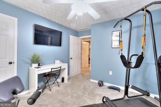 exercise room featuring a textured ceiling, light colored carpet, and ceiling fan