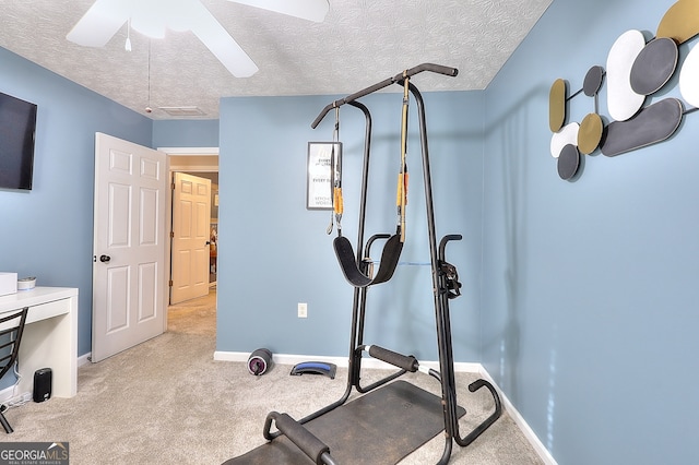 exercise room with ceiling fan, light colored carpet, and a textured ceiling