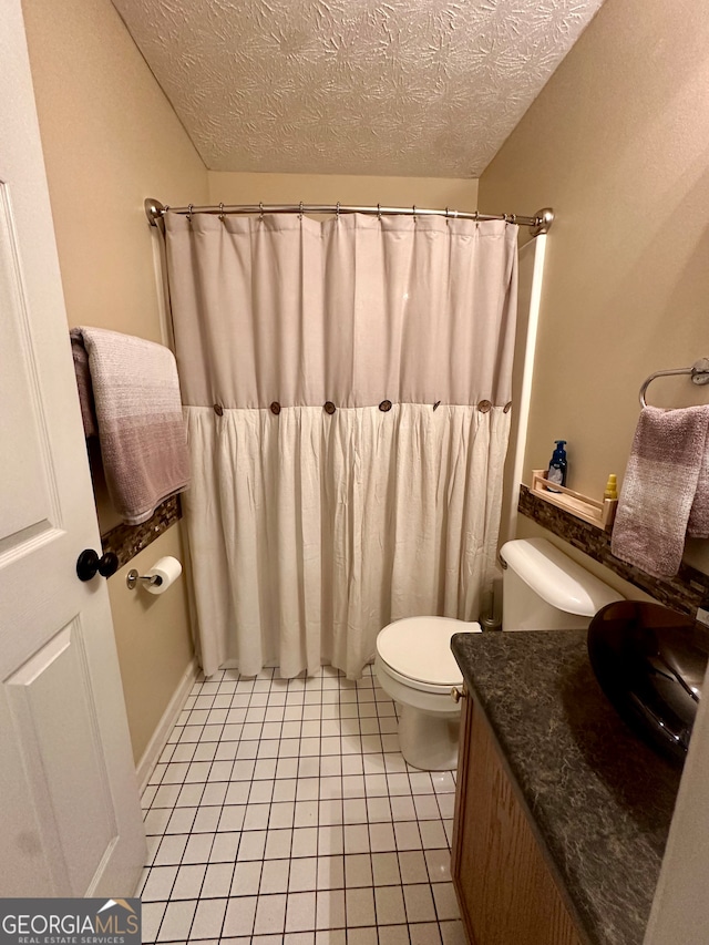 bathroom featuring tile patterned flooring, vanity, a textured ceiling, and toilet