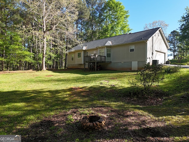 back of house featuring central air condition unit, a garage, and a lawn