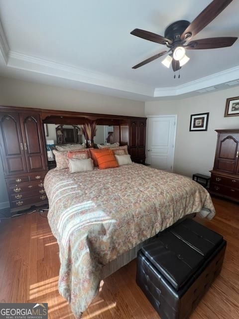 bedroom featuring dark hardwood / wood-style floors, a raised ceiling, ceiling fan, and ornamental molding