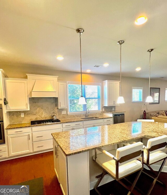 kitchen featuring a center island, a kitchen breakfast bar, sink, appliances with stainless steel finishes, and white cabinetry