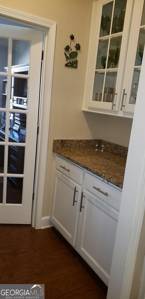 bar with white cabinetry, dark wood-type flooring, and dark stone countertops