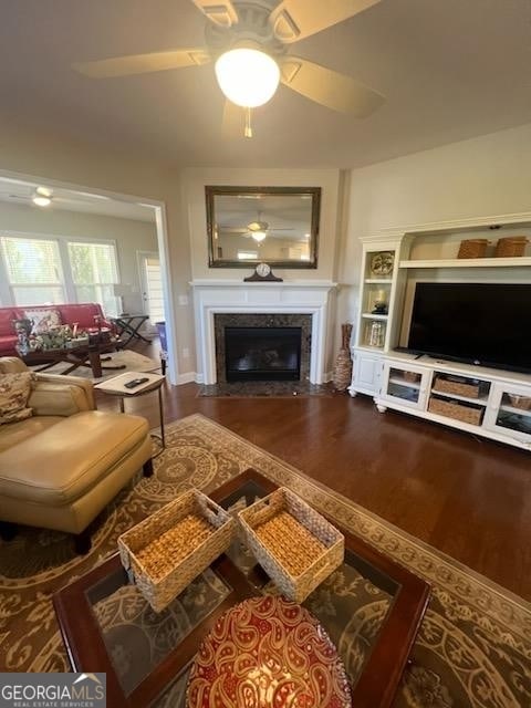 living room featuring hardwood / wood-style flooring, ceiling fan, and a premium fireplace